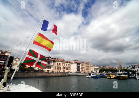 Trois drapeaux flottants à partir d'un mât du bateau, de bas en haut : drapeau Basque, drapeau espagnol, pavillon français, à St Jean de Luz, France Banque D'Images