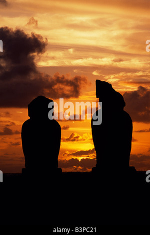 Le Chili, l'île de Pâques, Tahai. Le soleil se couche sur le Pacifique silhouetting deux des moais sur la plate-forme d'ahu Vai Uri au centre cérémoniel de Tahai. Tahai se trouve à quelques minutes de marche de l'île de Pâques Hanga Roa, sur la côte ouest de l'île, soutenue par l'océan Pacifique. Banque D'Images