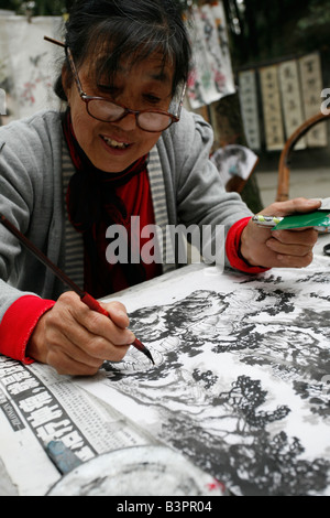 Femme chinoise peinture d'un paysage traditionnel chinois avec le pinceau et l'encre Banque D'Images