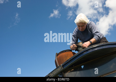 Homme nettoie la cuivrerie sur un vieux moteur de traction à vapeur vapeur à un rallye. Banque D'Images