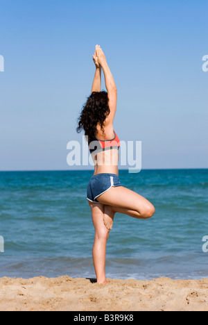 Parution du modèle fit young woman doing yoga des exercices d'étirement sur une plage de sable fin Banque D'Images