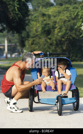 Père jogging avec 2 fils dans la poussette de bébé dans la région de park, Miami Banque D'Images