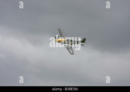 Un p51D Mustang dans un faible niveau passer à Duxford avec un ciel d'orage dans l'arrière-plan. Banque D'Images