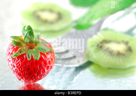 Les kiwis frais réfrigérés et les fraises à la menthe sur un fond réfléchissant avec une faible profondeur de champ Banque D'Images