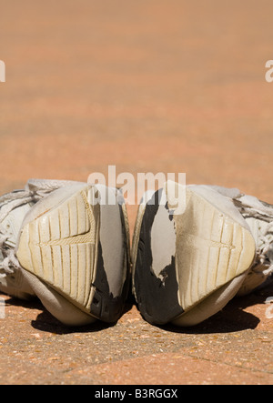 Une paire de vieilles chaussures de formation usés sur un patio Banque D'Images