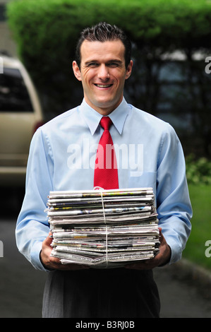 Conscient de l'environnement homme portant une pile de journaux pour être recyclés Banque D'Images