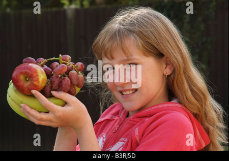 Main de bananes une pomme et un peu de raisin dans une main les jeunes filles Banque D'Images