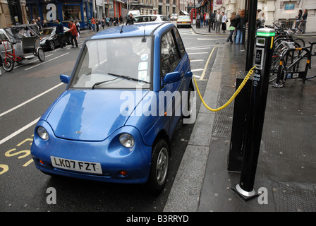 Une voiture électrique (une Reva G Wiz voiture électrique neutre en carbone) permet de charger jusqu'à l'aide d'un point de jus de rue dans le centre de Londres Banque D'Images