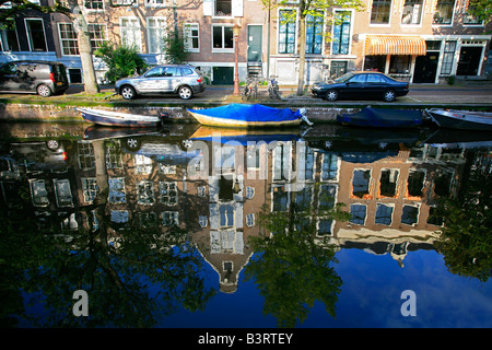 Rue typique d'Amsterdam le long de canal avec des vélos hollandais, bateaux, voitures et maisons reflet dans l'eau en début de l'été, matin, Amsterdam, Pays-Bas Banque D'Images