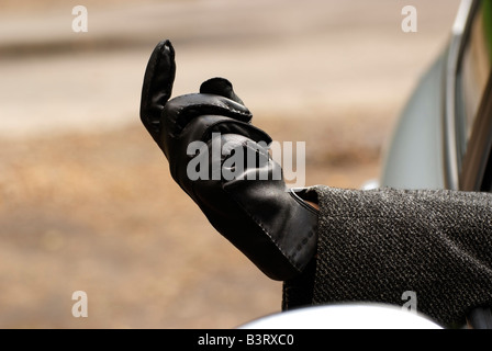 Une main gantée de cuir noir de l'automobiliste s'étend de la fenêtre les conducteurs de voiture Banque D'Images