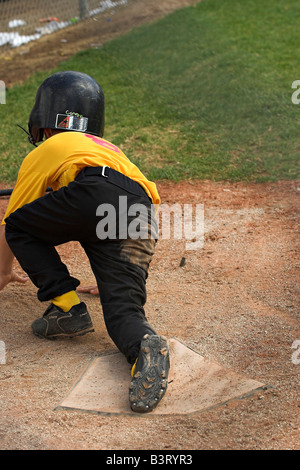 Un jeune homme se glisse dans la maison pendant un coach-pitch, peu d-league jeu. Banque D'Images