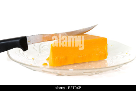 Un morceau en forme de triangle de fromage cheddar avec couteau sur une petite plaque de verre taillé sur fond blanc. Banque D'Images