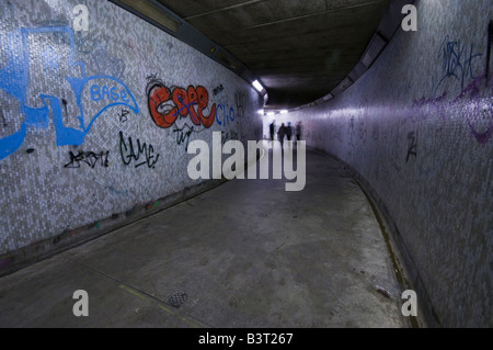 Le métro la nuit, montrant grafitti, avec 4 adolescents marche à travers Banque D'Images