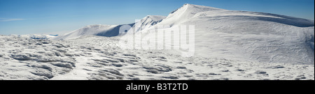 La crête de montagnes d'hiver avec dépassement des plafonds de la neige et des pistes de snowboard sur fond de ciel bleu Banque D'Images