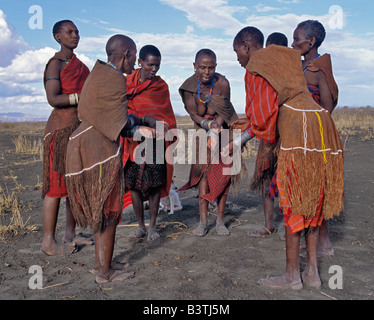 La Tanzanie, le nord de la Tanzanie, de Manyara. Vieilles femmes portant de Datoga décorées magnifiquement tannées et robes en cuir chanter une courte distance de leur maison. Ils garder le rythme en frottant leurs nombreux bracelets de fer ensemble.Les Datoga (connus pour leurs voisins comme le Maasai Mang'ati et pour les Iraqws comme Babaraig) vivent dans le nord de la Tanzanie et sont principalement des éleveurs. Banque D'Images