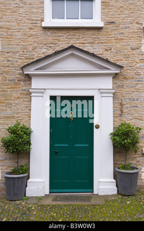 Porte avant vert blanc avec fronton triangulaire de townhouse in Ludlow Shropshire England UK avec arbustes Banque D'Images