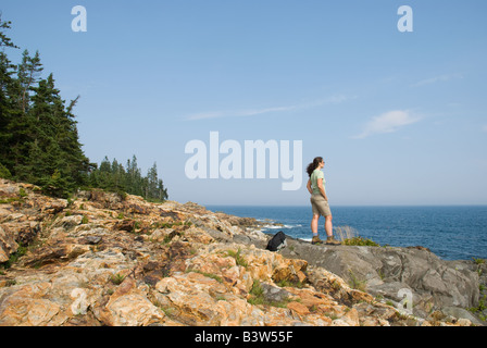 Une femme se tient sur la côte rocheuse du Maine Acadia National Park Banque D'Images