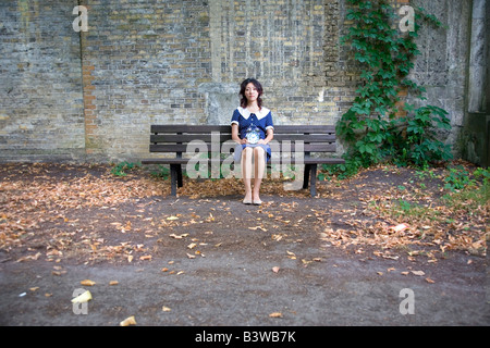 Japanese girl sitting on banc en bois avec un réveil Banque D'Images