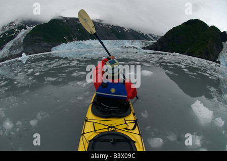 Un homme de kayaks de mer de glace bergs creux en face de trois le vêlage des glaciers dans les bras de Barry dans le Prince William Sound, Alaska Banque D'Images