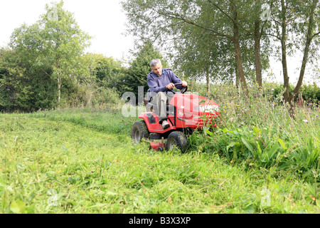 Man mowing lawn sur une tondeuse à Banque D'Images