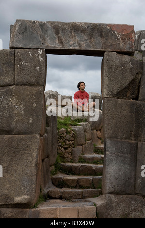 Un jeune homme médite dans les anciennes ruines Incas en dehors de Cuzco, Pérou Banque D'Images