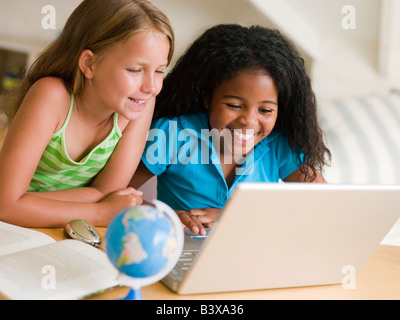 Deux jeunes filles faisant leurs devoirs sur un ordinateur portable Banque D'Images