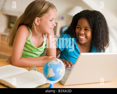 Deux jeunes filles faisant leurs devoirs sur un ordinateur portable Banque D'Images