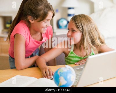 Deux jeunes filles à faire leurs devoirs sur un ordinateur portable Banque D'Images