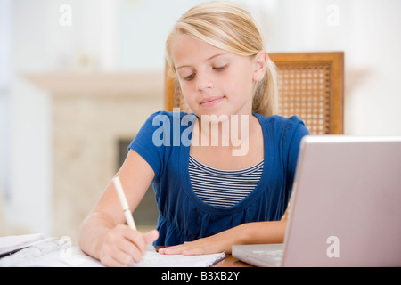 Jeune fille à faire des devoirs et à l'aide d'ordinateur portable Banque D'Images