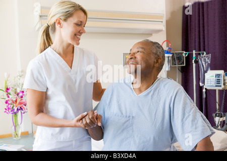 Nurse Helping Patient s'asseoir au lit Banque D'Images