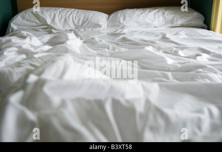 Lit non fait draps de lit blancs froissés froissés et échevelés HOMER SYKES Banque D'Images