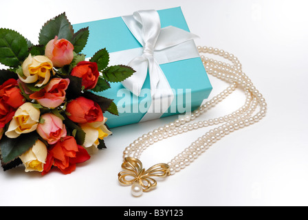 Une élégante boîte cadeau bleue peu que chacun souhaite recevoir avec un collier de perles et de fleurs Banque D'Images