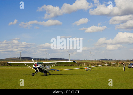 Maule M6-235 remorqueur prêt à lancer un planeur ASW15B à la ferme. L'Watchfield éoliennes sont visibles dans l'arrière-plan. Banque D'Images