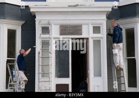 Deux peintres peinture échelles debout sur la façade à l'extérieur d'un bâtiment Banque D'Images