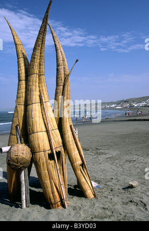 Le Pérou, La Libertad, Huanchaco. Totora (Reed) bateaux de pêche sont empilées sur la plage de Huanchaco, dans le nord du Pérou. Les bateaux appelés caballitos de Totora (petits chevaux de roseaux) sont l'artisanat traditionnel des pêcheurs locaux (pescadores). Banque D'Images