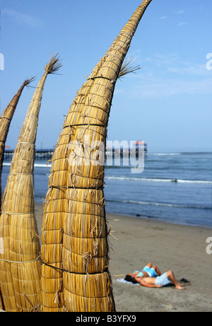 Le Pérou, La Libertad, Huanchaco. Caballitos de Totora (roseaux) bateaux sont empilés le long de la plage à sécher à Huanchaco au nord du Pérou. Les bateaux ont été utilisés par les pêcheurs sur la côte nord du Pérou pendant plus de deux mille ans. Banque D'Images