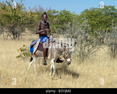 La Namibie, Kaokoland. Un jeune Himba tours pour marché sur un âne. Ses cheveux sont aménagées dans une longue natte, connu comme ondatu. Une fois mariés Banque D'Images