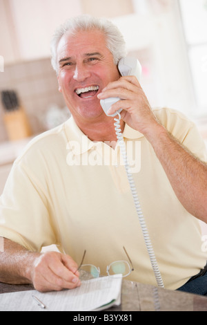 Man in kitchen sur téléphone laughing Banque D'Images