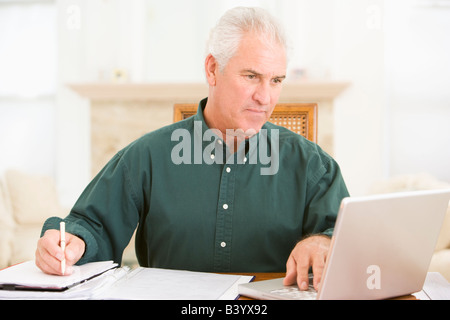 L'homme dans la salle à manger avec un ordinateur portable et de la paperasserie Banque D'Images