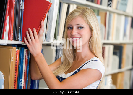 Femme en tirant un livre de bibliothèque étagère (profondeur de champ) Banque D'Images