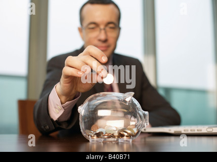 Businessman putting une pièce dans une tirelire Banque D'Images