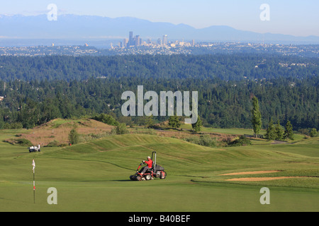 Tôt le matin, avec le Seattle skyline en arrière-plan, les Verts Crew préparer le Newcastle Golf Club pour jouer. Banque D'Images