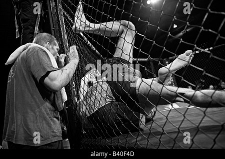 Deux combattants de la cage dans l'octogone du côté de la pince (Cage) Trainer sur les montres. Banque D'Images