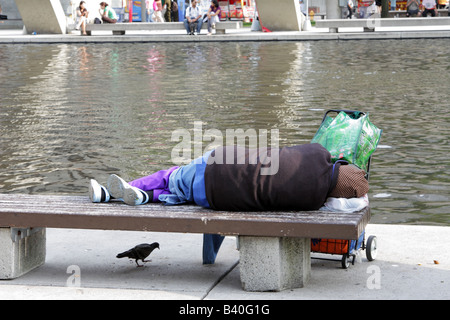 Femme sans-abri dormant dans un banc au Nathan Phillips Square de Toronto Banque D'Images