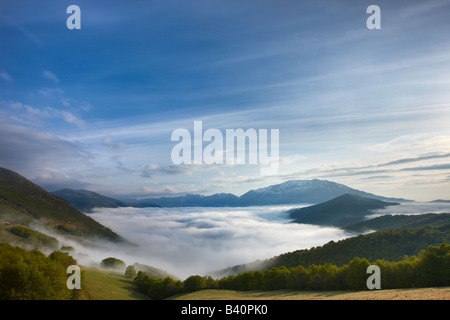 Mist couché sur le Piano Grande à l'aube avec les montagnes du parc national Monti Sibillini se lever au-dessus, de l'Ombrie, Italie Banque D'Images
