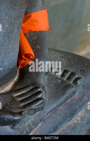 Close up detail de main de Bouddha en pierre, le pied et le bras avec écharpe orange, Angkor Wat, au Cambodge Banque D'Images