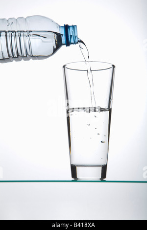 Boire dans un verre rempli d'une bouteille en plastique Banque D'Images