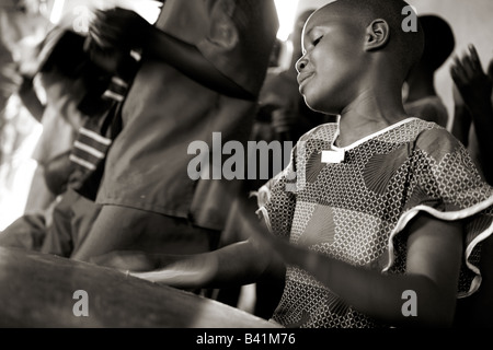 Une jeune fille joue le tambour lorsqu'elle dirige le chœur d'enfants à Gisenyi, au Rwanda. Banque D'Images