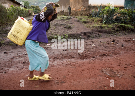 Une jeune femme rwandaise transporte l'eau du puits, un travail ardu que le jerrican 20 litres pèse 44 livres lorsqu'il est plein. Banque D'Images