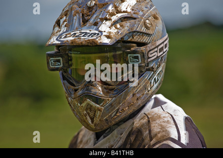 Homme avec un casque qui participent à des courses de motocross avec casque et protections des yeux couverts de boue Banque D'Images